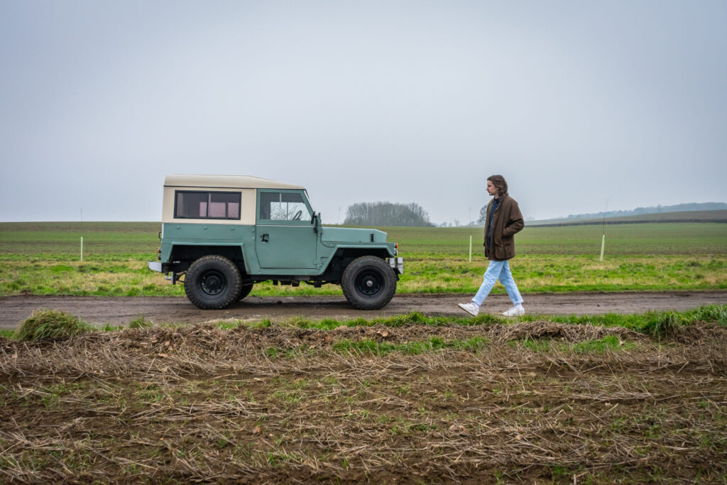 Country hiker admiring a Land Rover Lightweight in the countryside while walking past.